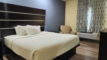 Una habitación de hotel moderna con una cama grande, una silla, un escritorio y una ventana con cortinas estampadas.