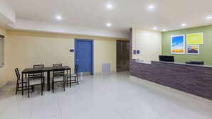 A hotel lobby with a reception desk, a blue door, and a dining area with tables and chairs. - Days Inn by Wyndham Baton Rouge Airport (Baton Rouge)