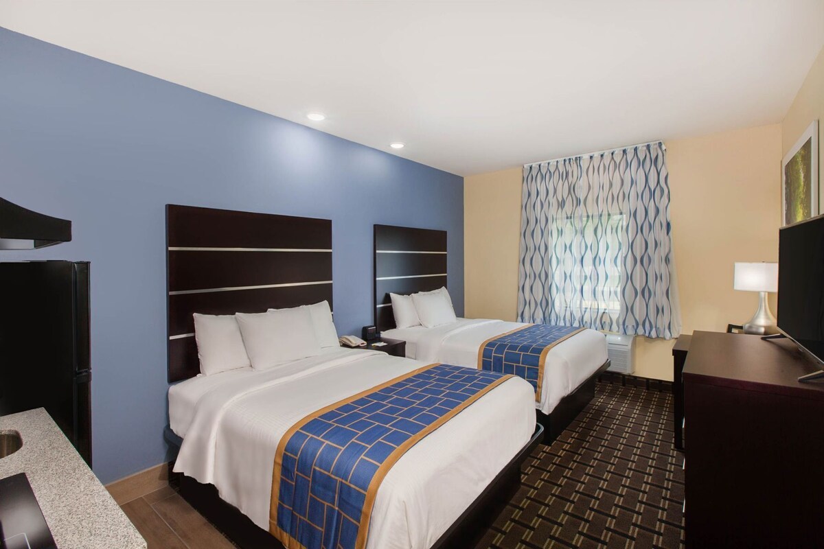 Une chambre d’hôtel avec deux lits, un bureau, une télévision et un rideau à motifs.