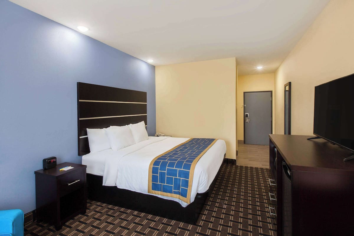 A hotel room with a bed, a TV, a desk, and a nightstand.