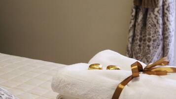 A neatly made bed with a white towel and a gold ribbon.