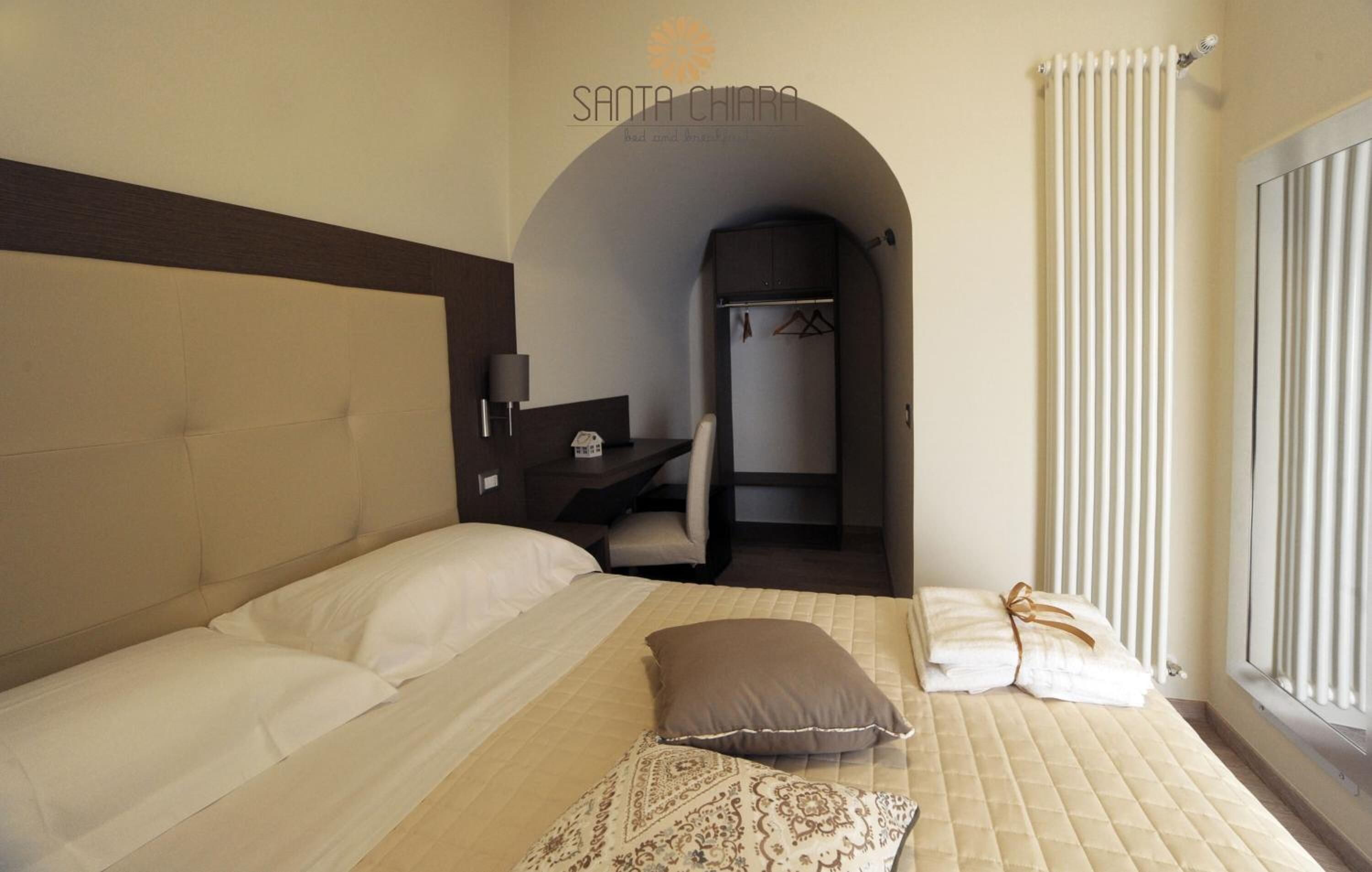 A hotel room with a bed, a desk, and a bathroom visible through an archway.