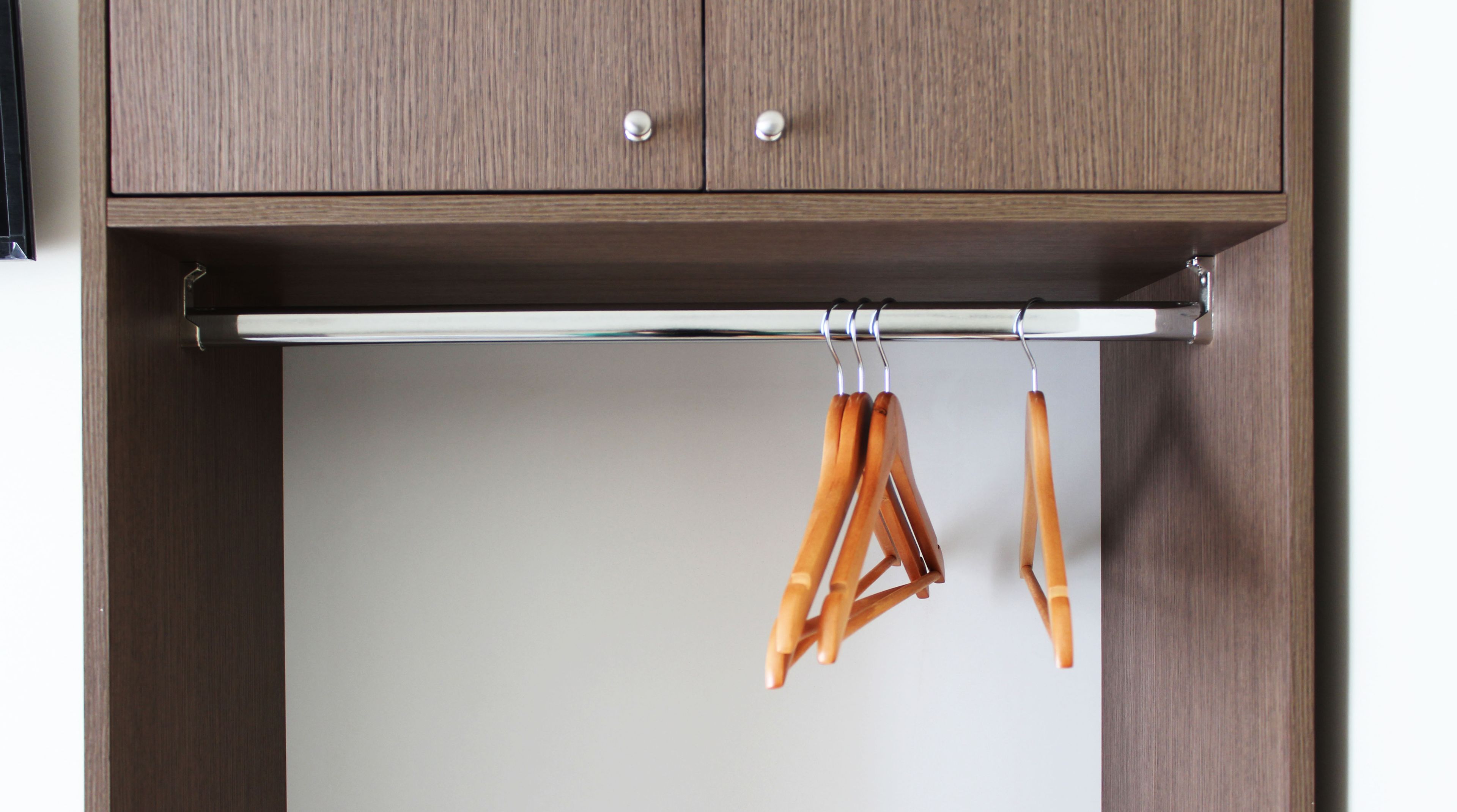 A wooden wardrobe with two doors and a hanging rod.