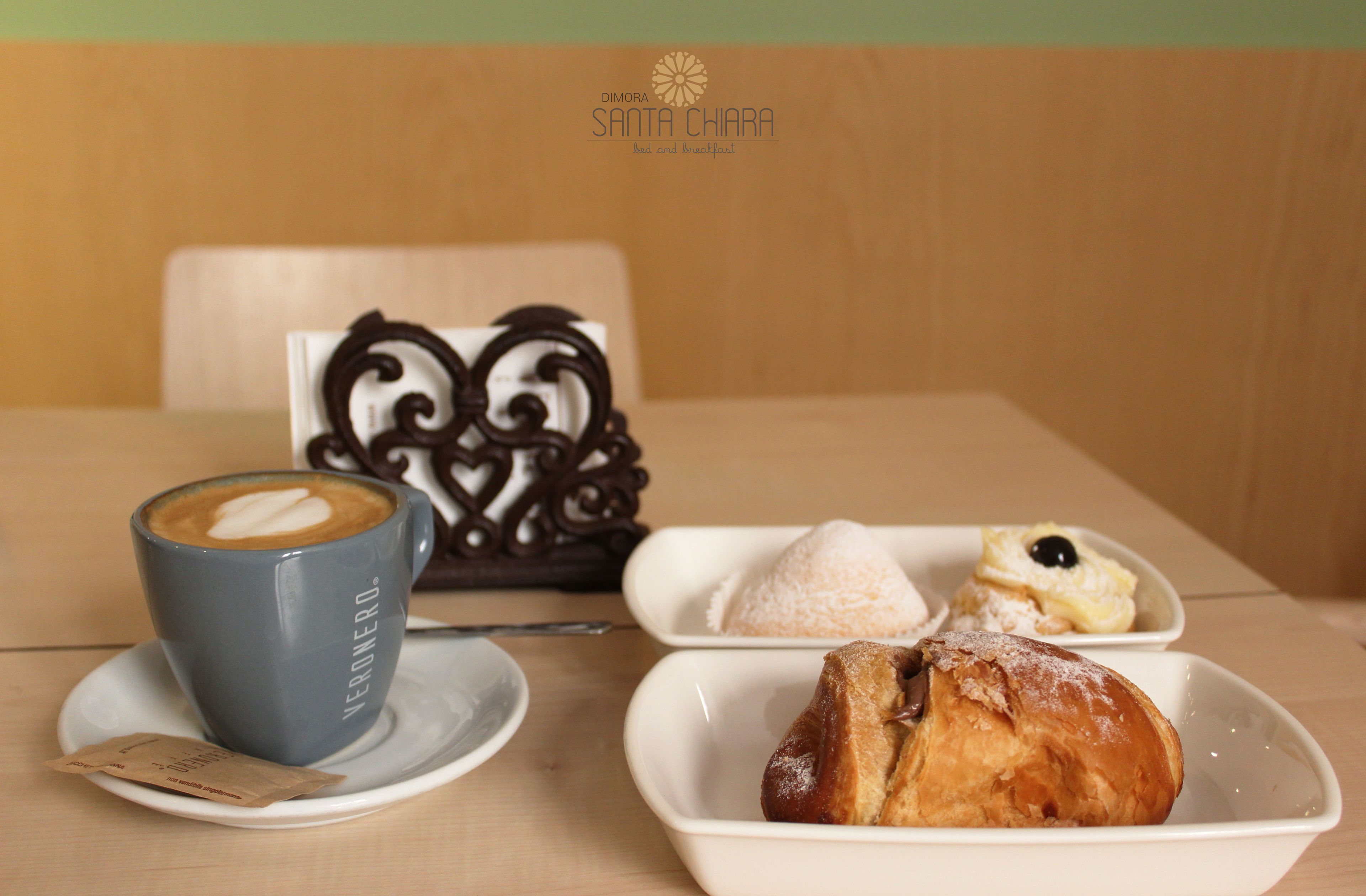 A table with a cup of coffee, a pastry, and a decorative item.