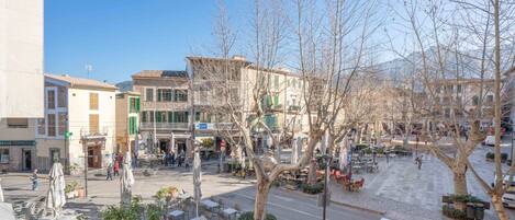 A street view with buildings, outdoor seating, and trees.