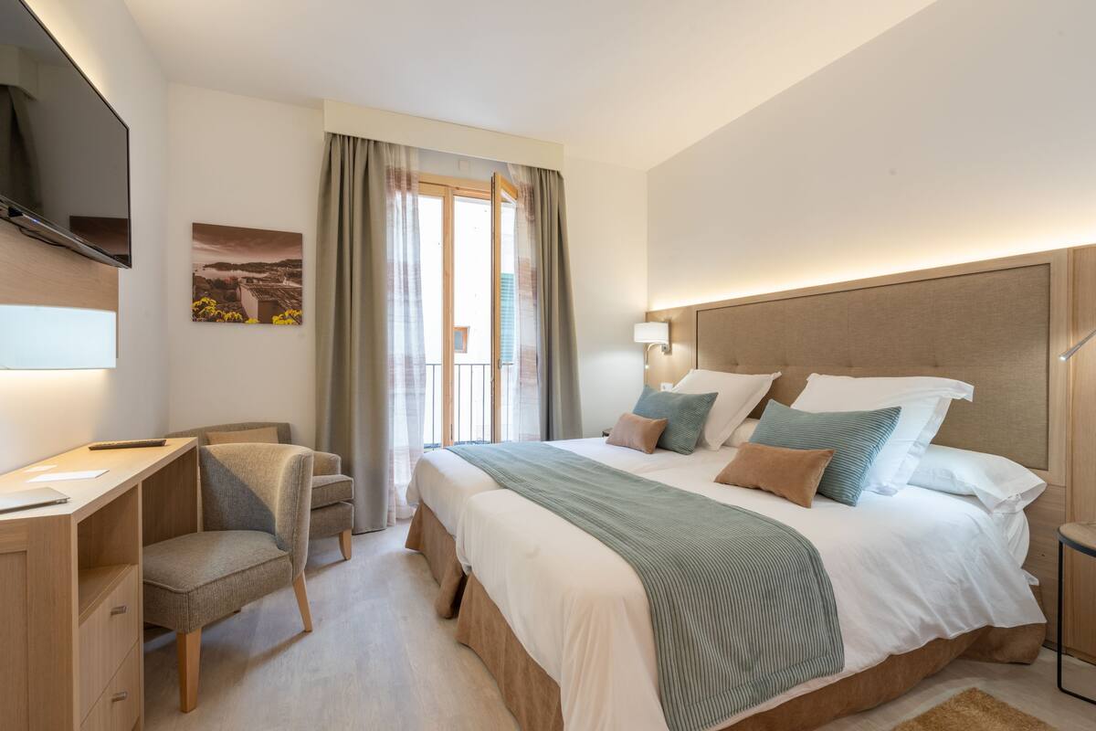 Ein modernes Hotelzimmer mit einem großen Bett, einem Schreibtisch und einem Fernseher.