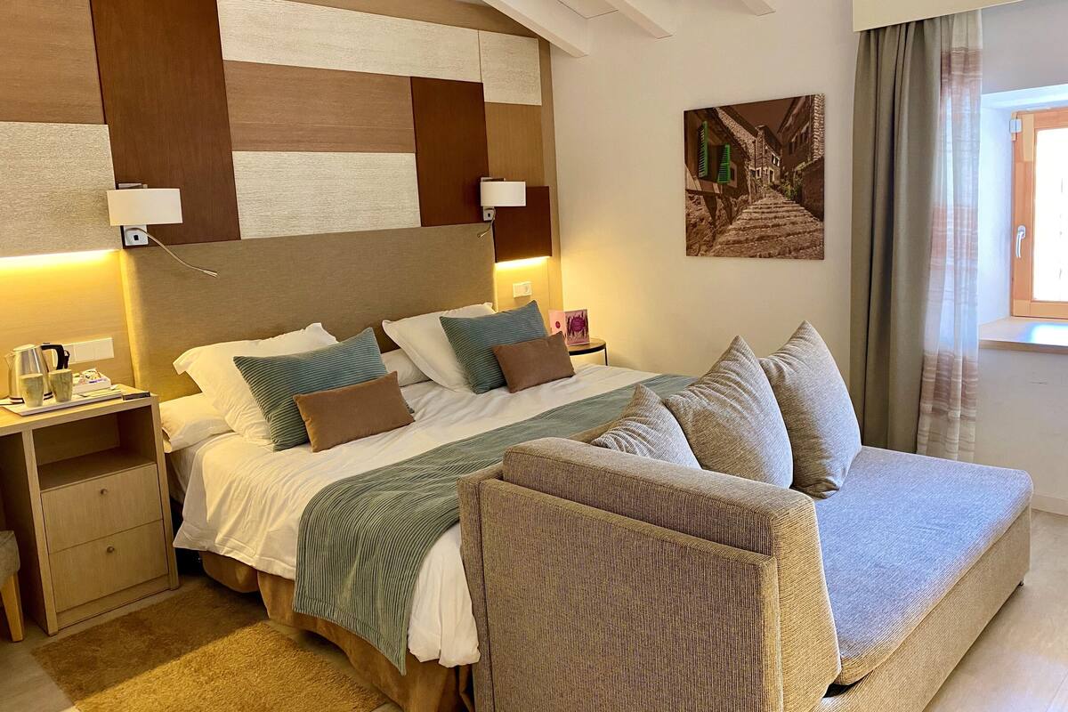 Ein Hotelzimmer mit einem großen Bett, Nachttischen, einer Couch und einem Gemälde an der Wand.