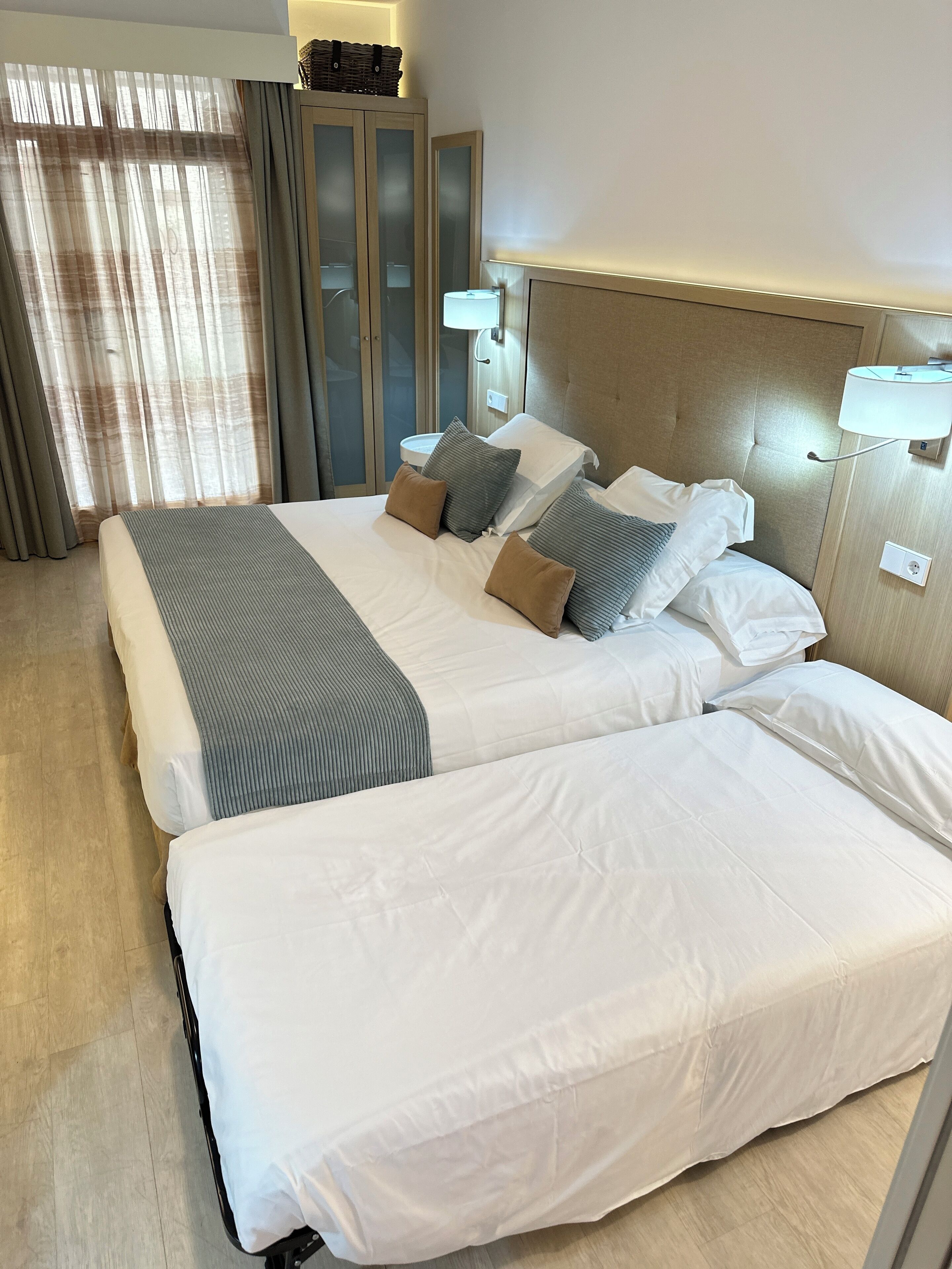 A hotel room with a large bed, a bedside table, a lamp, and a wardrobe.
