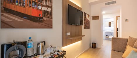 Una sala moderna con un televisor de pantalla plana montado en una pared de madera, una cafetera y una mesa con una cesta.
