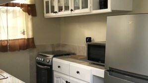 Une cuisine avec des meubles blancs, un réfrigérateur en acier inoxydable, un four à micro-ondes et une cuisinière.