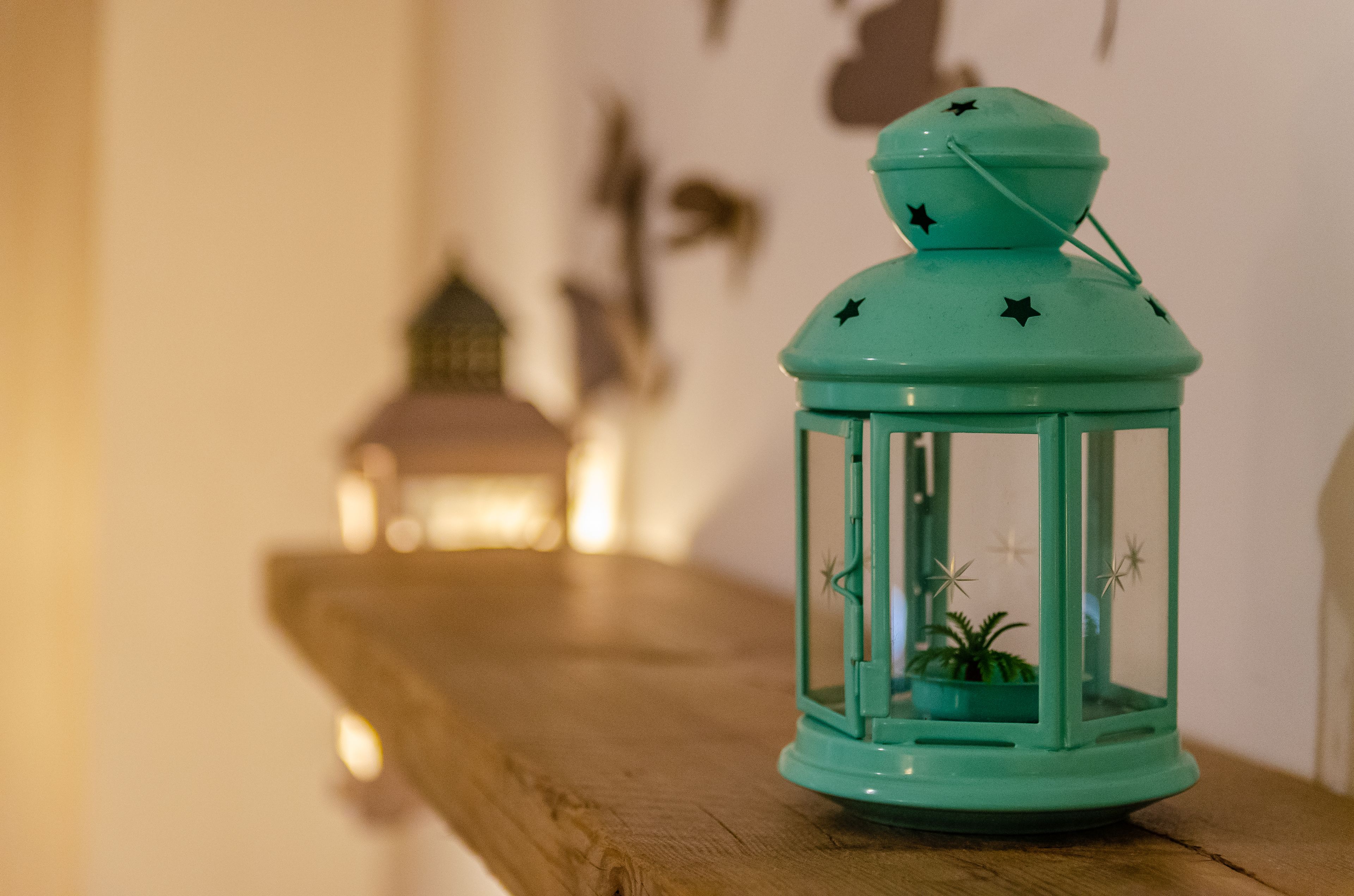 Un farolillo azul verdoso con estrellas sobre una superficie de madera.