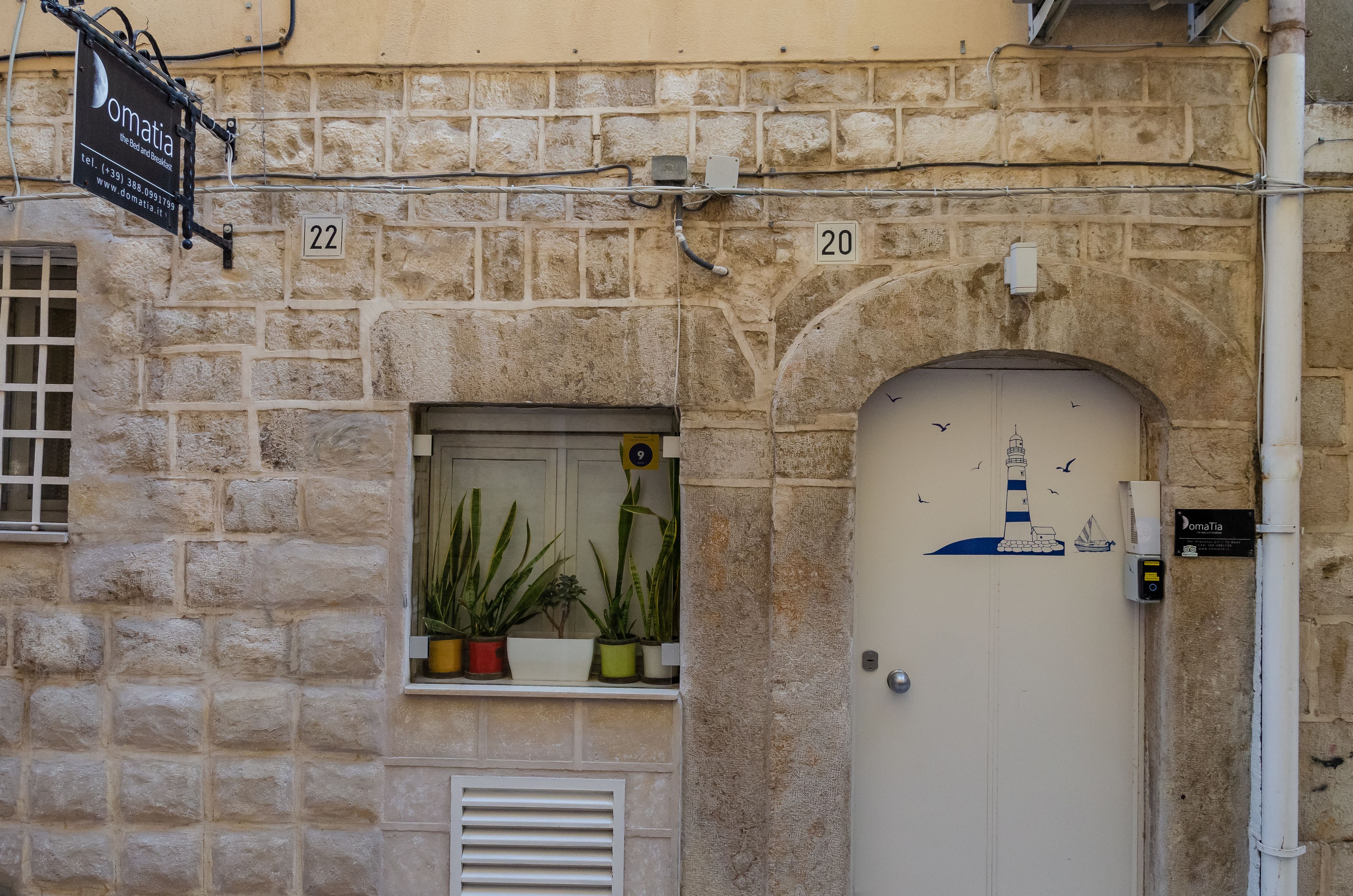 Un edificio de piedra con un letrero que dice 'Omatia' y puertas numeradas 20 y 22.