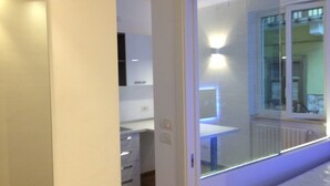 A modern room with a glass door leading to a balcony, a white desk, and a chair. - Domatia (Barletta)