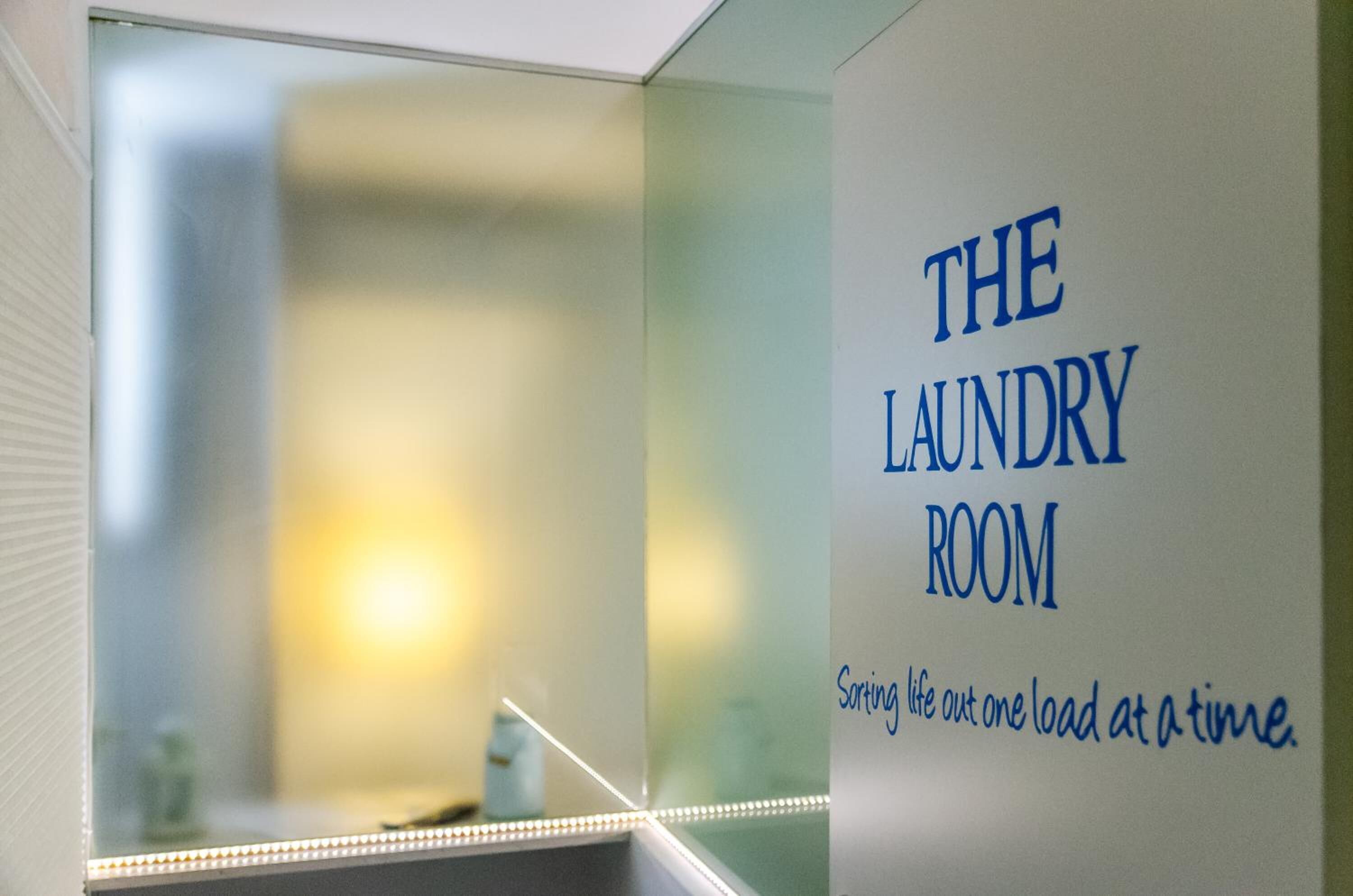 A wall with the text "THE LAUNDRY ROOM" and a slogan "Sorting life out one load at a time."