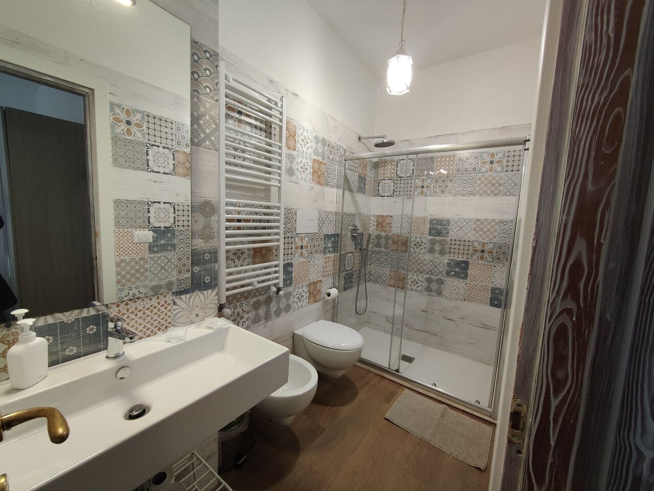 A bathroom with a white sink, toilet, and glass shower enclosure.