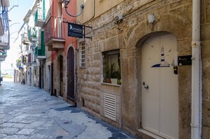 Una calle estrecha bordeada de edificios, incluyendo un hotel con un letrero que dice "Domatia".