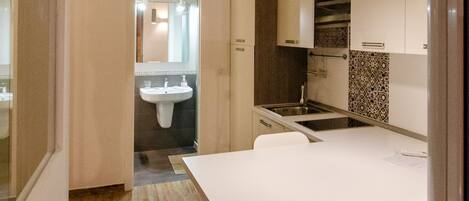 A modern kitchen with a white countertop, a sink, and a stove.