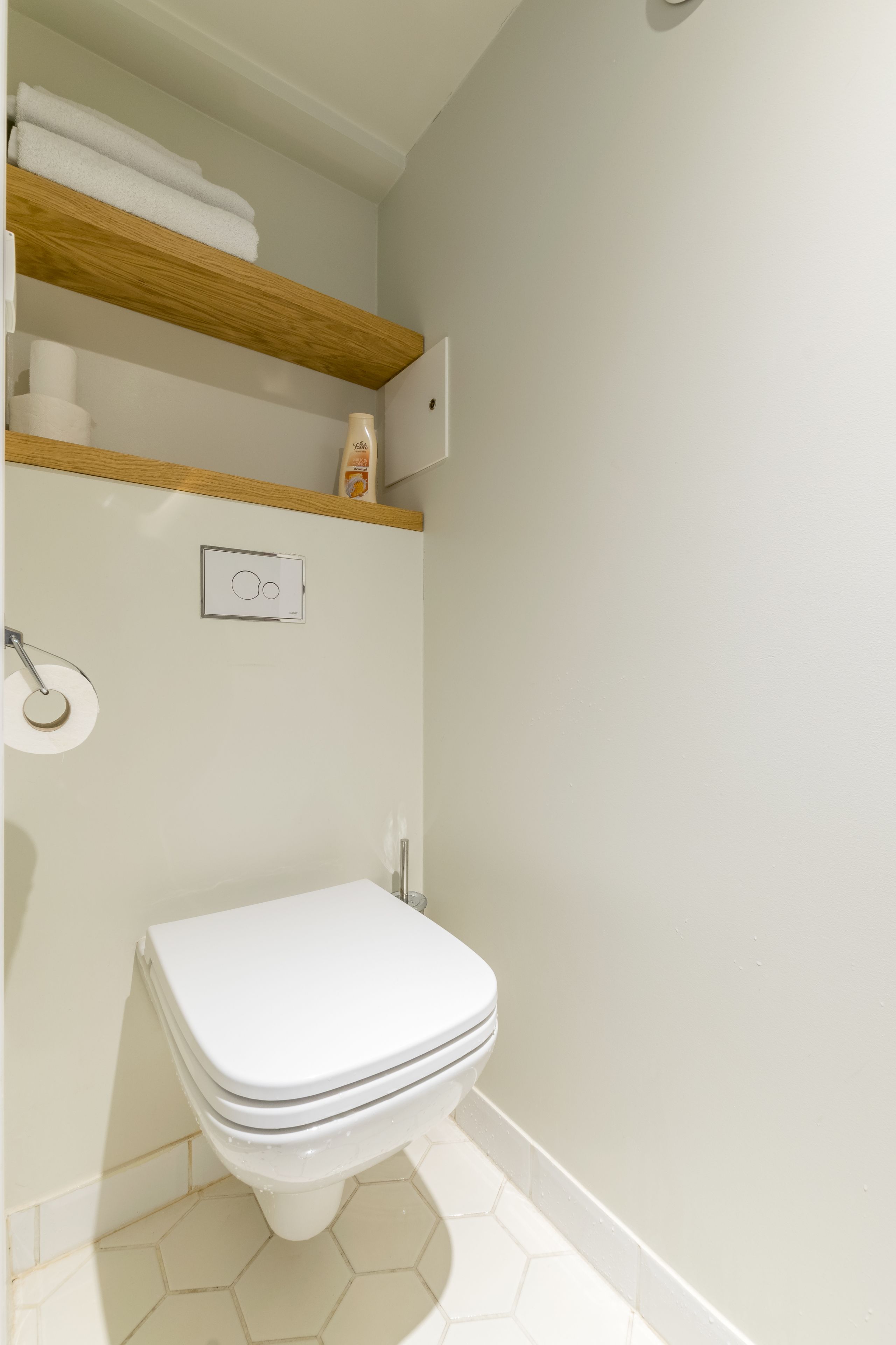 A bathroom with a toilet, a towel rack, and a toilet paper holder.