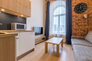 A modern kitchen with a microwave, a TV, and a wooden table.