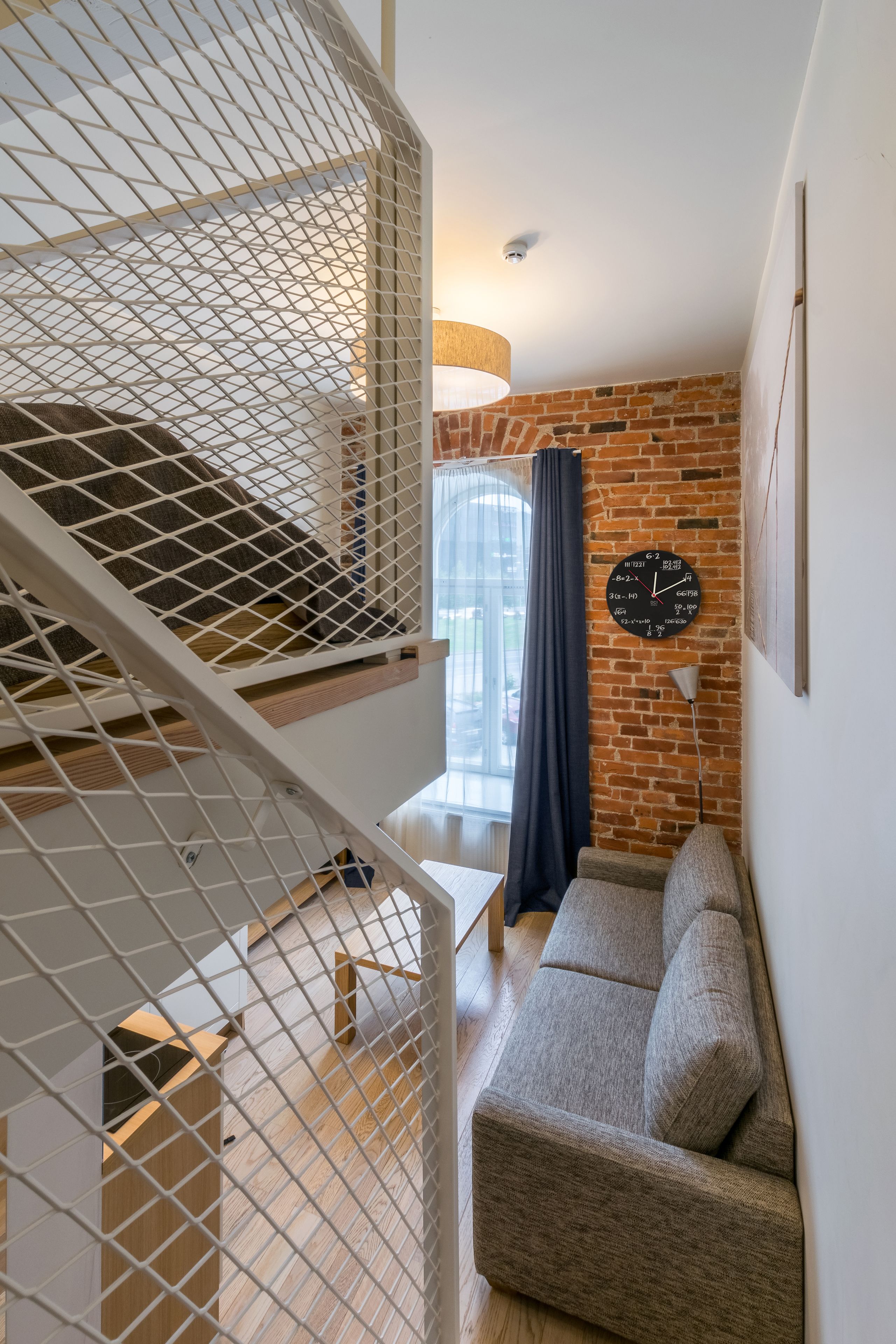 Un espace de vie moderne comprenant un escalier, un canapé et une horloge murale.