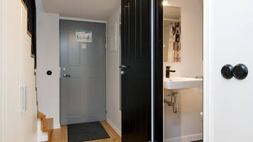 A hallway with a grey door, a black door, a white sink, and a black toilet.