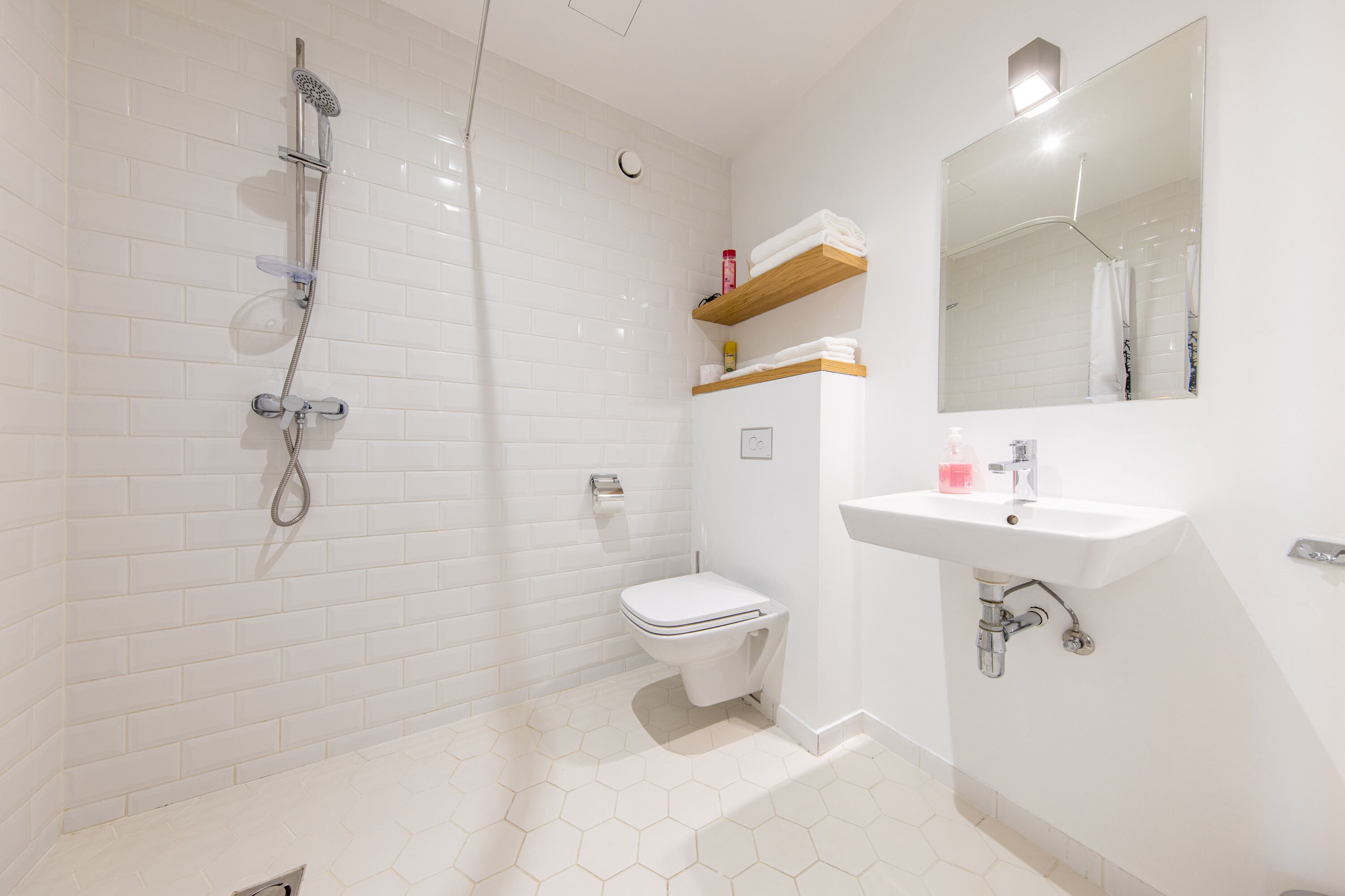 A bathroom with a shower, toilet, sink, and mirror.