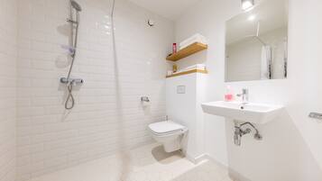 A bathroom with a shower, toilet, sink, and mirror.