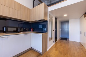 A modern kitchen with white cabinets, a microwave, and a coffee maker.