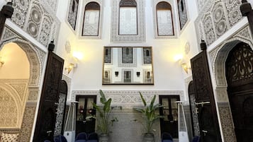 Relax by the central pool surrounded by comfortable seating areas and intricate patterns on the walls and ceiling.