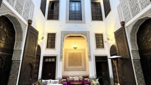 Un interior con arcos decorativos, una zona de estar central y suelo estampado.