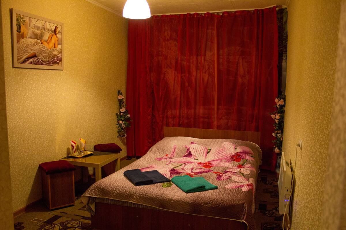 A hotel room with a bed, a desk, a chair, and a painting on the wall.