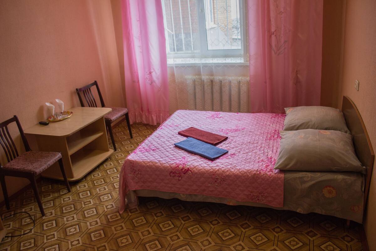A bedroom with a bed, a desk, and a chair.