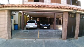 Un área de estacionamiento techada con dos coches aparcados bajo un tejado de baldosas.