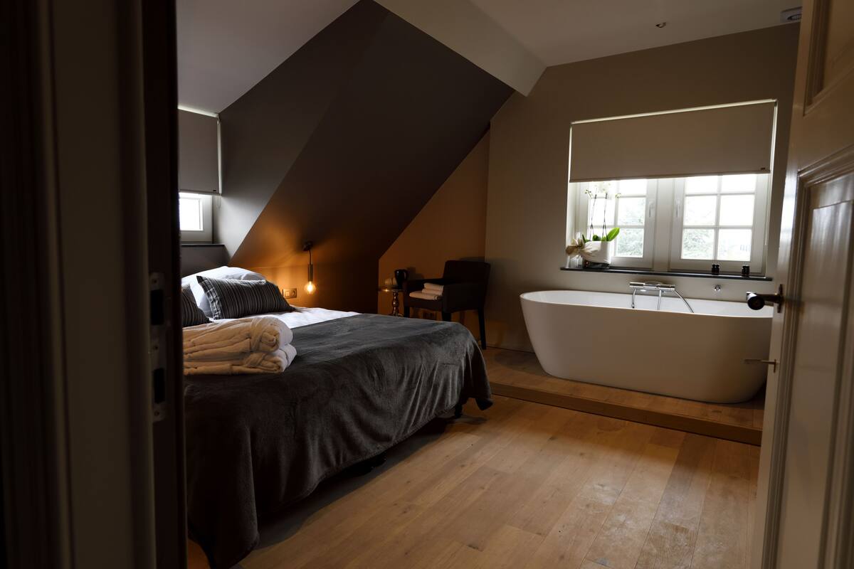 Een slaapkamer met een groot bed, een badkuip en een raam met uitzicht op de omgeving.