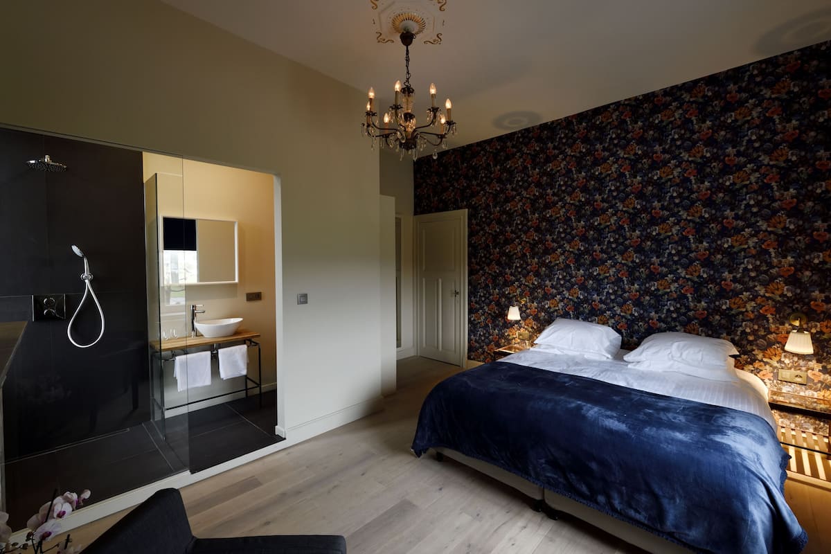 Een moderne slaapkamer met een groot bed, een douchegedeelte en een wand met een bloemenprint.