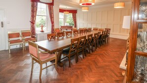 Un comedor con una larga mesa de madera, varias sillas y dos candelabros.