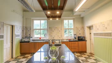 A kitchen with a central island, two windows, and patterned wallpaper.