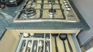 Cozinha com fogão a gás, pia e gaveta com utensílios.