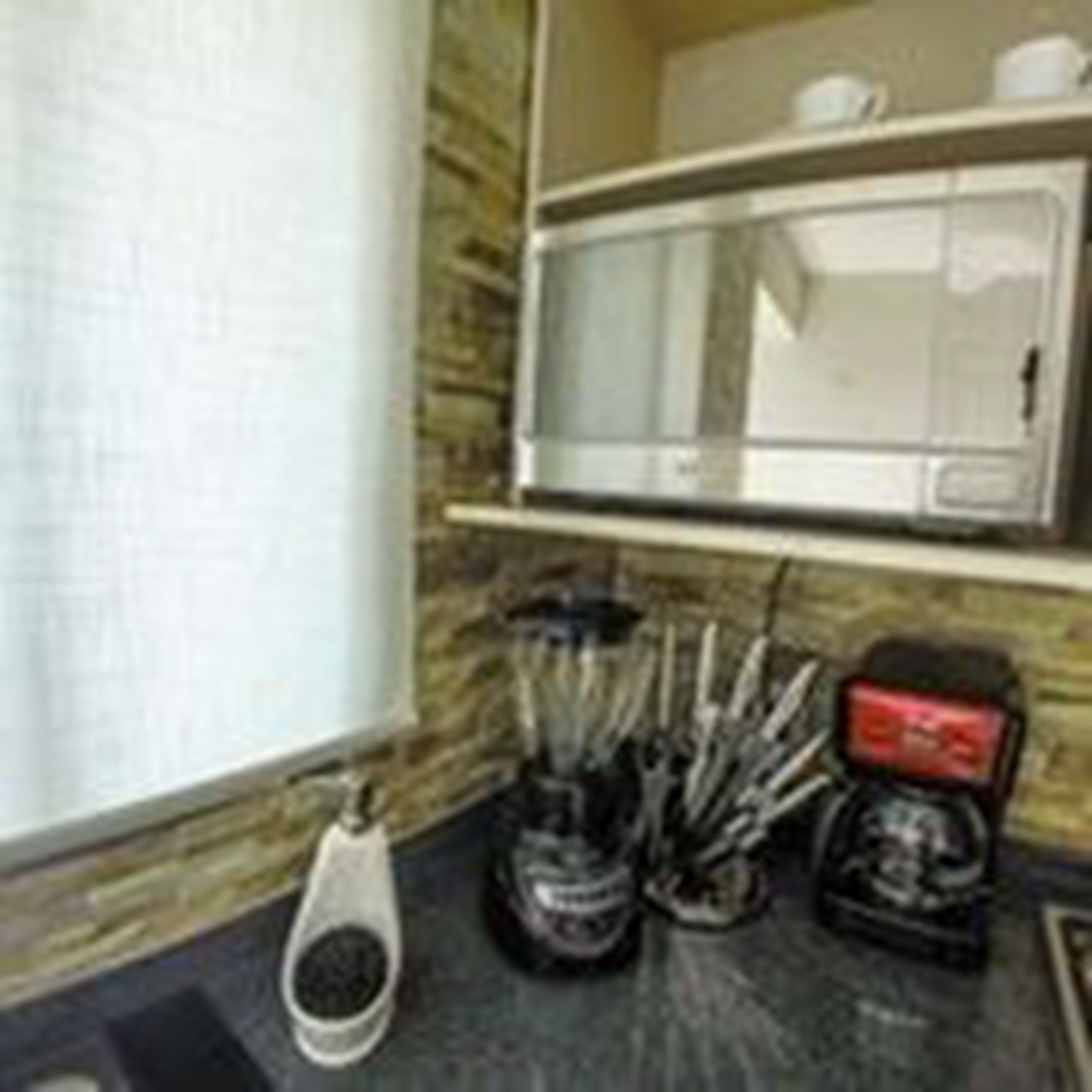 A kitchen with a microwave, coffee maker, and utensils on the counter.