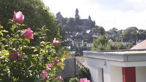 A view of a castle on a hill with pink flowers in the foreground. - Ferienwohnungen Schlossblick (Braunfels)