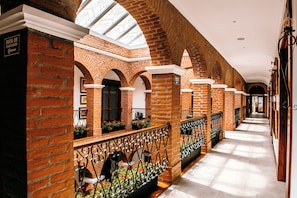 A corridor with brick walls, arched doorways, and a skylight.