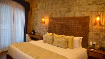 A hotel room with a large bed, stone walls, and two bedside lamps.
