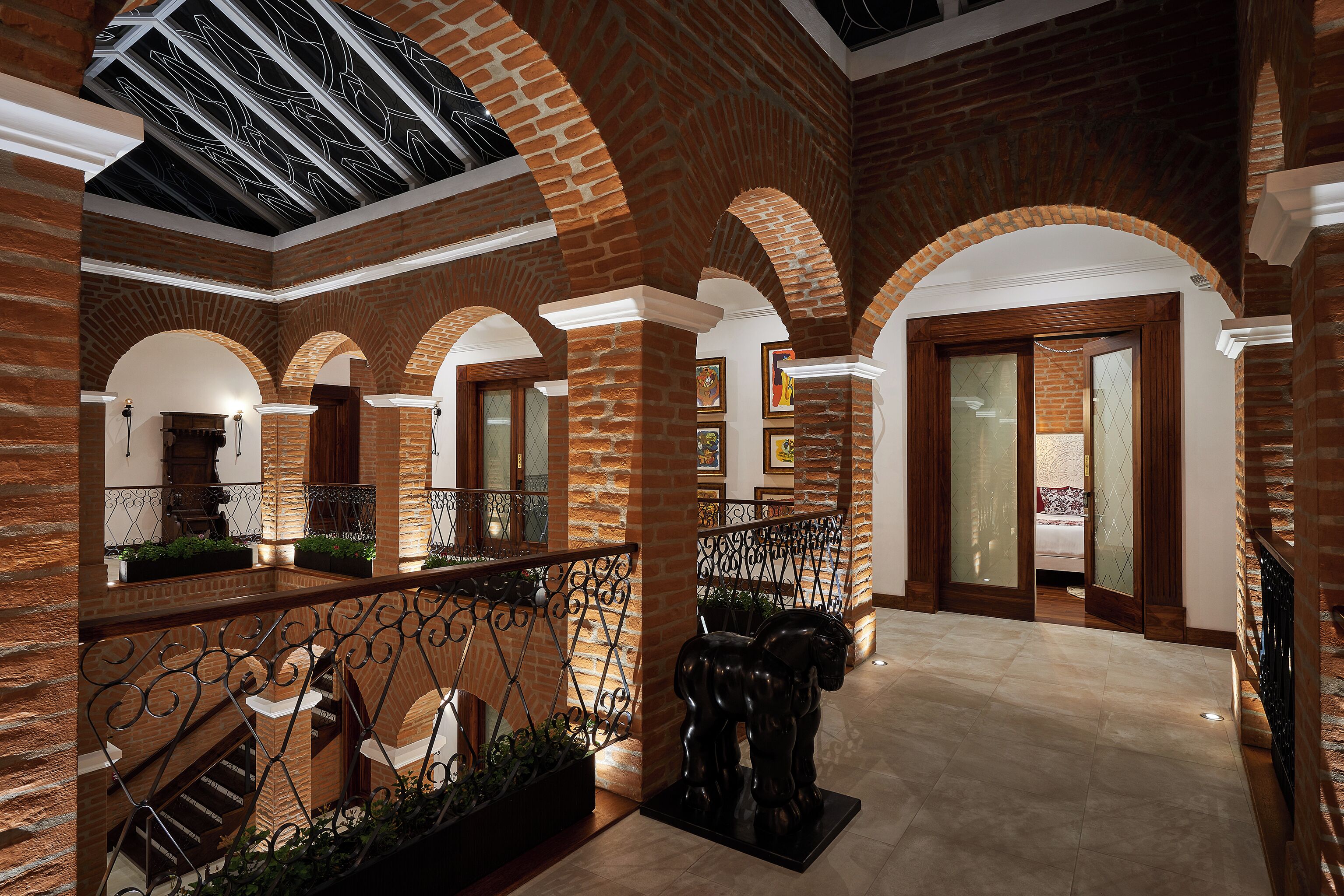 A spacious interior with brick arches, a balcony with metal railings, and a central statue.