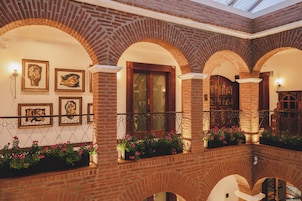 Un edificio de ladrillo con ventanas de arco y un balcón con macetas de flores.