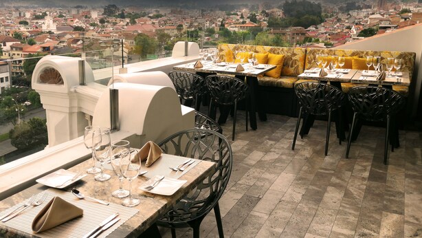 A restaurant with outdoor seating overlooking a cityscape and mountains. - Hotel Cruz del Vado by Art Hotels Ecuador (Cuenca)