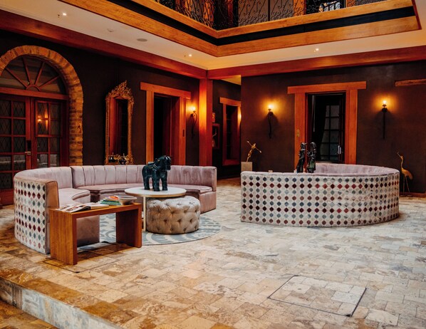 A spacious lobby with a curved sofa, ottoman, and a patterned ottoman. - Hotel Cruz del Vado by Art Hotels Ecuador (Cuenca)