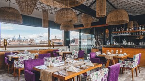 Un restaurante con mesas dispuestas para comer, lámparas de techo de mimbre y vistas a la ciudad.