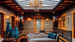 A room with a wooden bench, large vases, a chandelier, and a view through a skylight. - Hotel Cruz del Vado by Art Hotels Ecuador (Cuenca)
