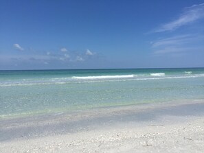 A beach with clear turquoise water and a sandy shore.