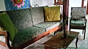 Uma sala de estar com sofá, mesa de centro de madeira e uma poltrona.